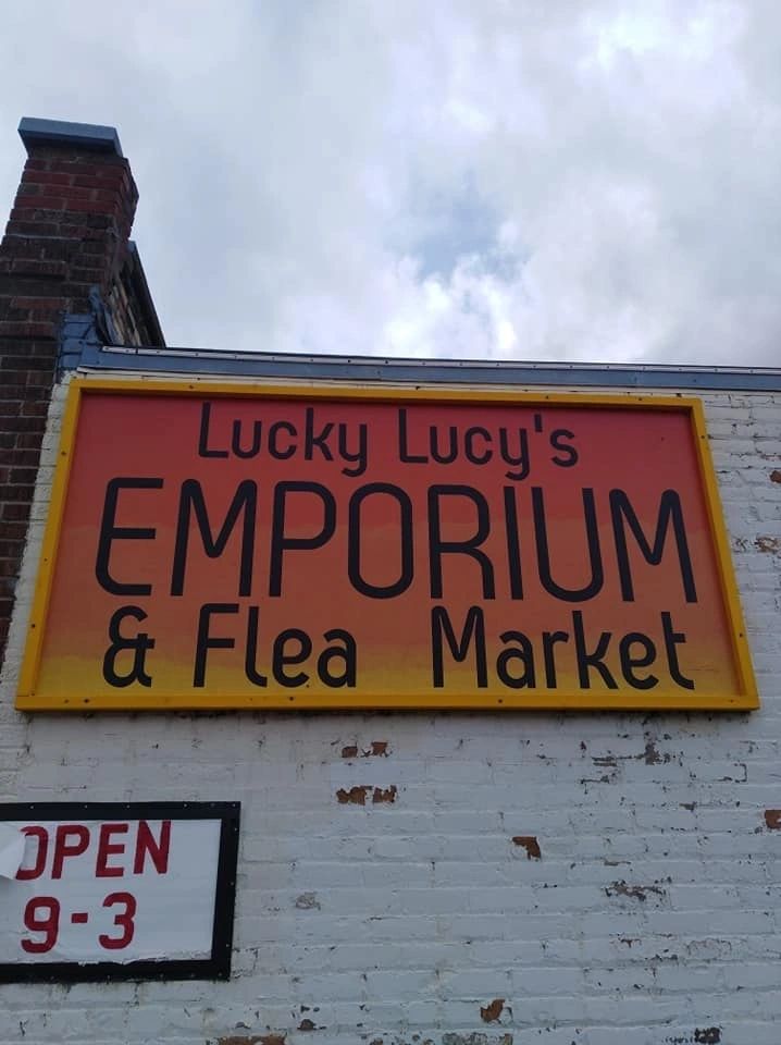 Lucky Lucy's Emporium & Flea Market storefront sign — Open 9-3
